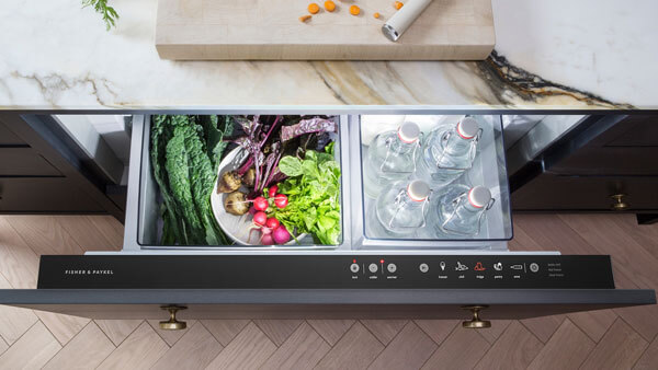 Réfrigérateur CoolDrawer intégré ouvert et rempli de légumes frais et de bouteilles d’eau