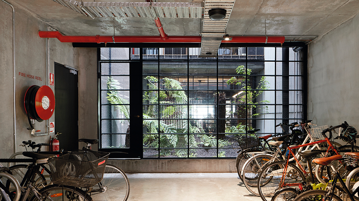 Garage de style industriel en béton avec une fenêtre à carreaux noirs et de nombreux vélos.