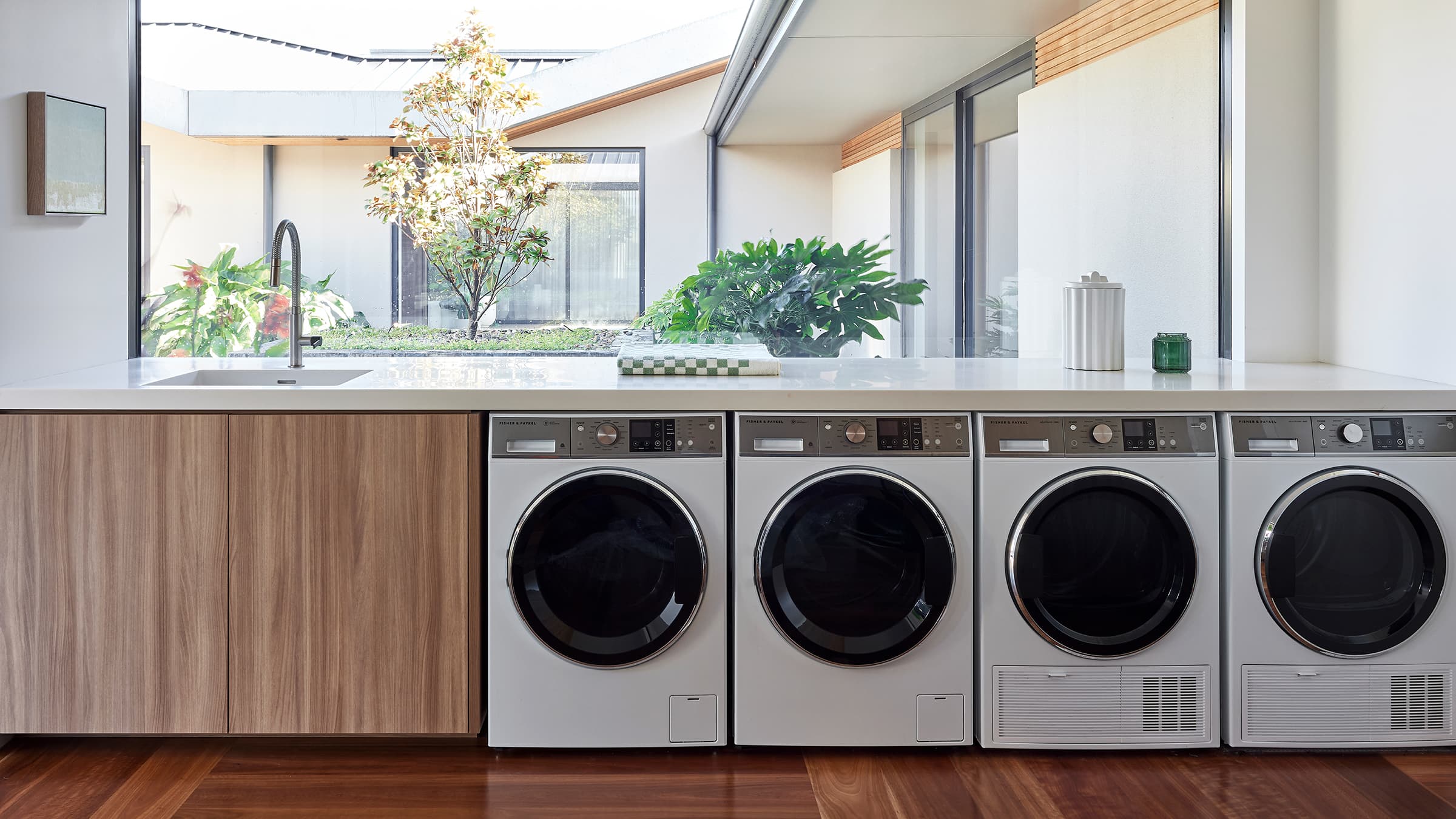 Shot of the hallway and laundry, showcasing four large-capacity Fisher & Paykel Washer Dryers