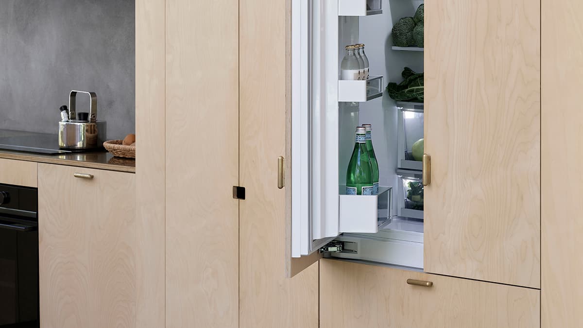 Kitchen view showing the integrated French Door Refrigerator with one door open, alongside the lounge area