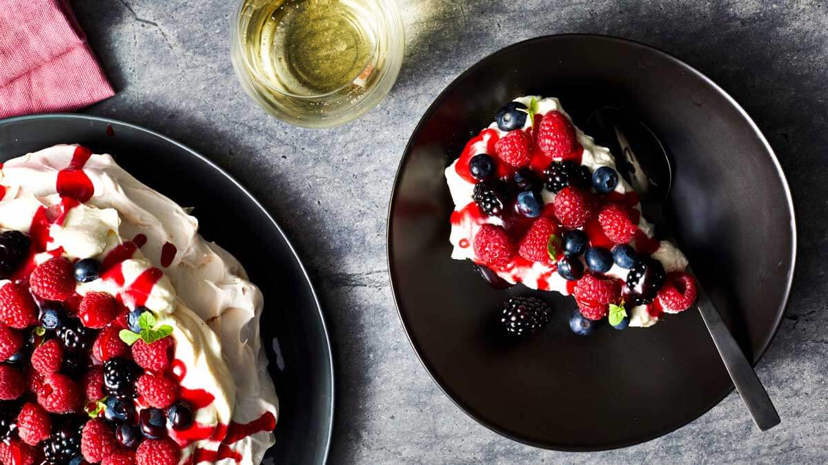 Berry Compote Pavlova with a Glass of White Wine