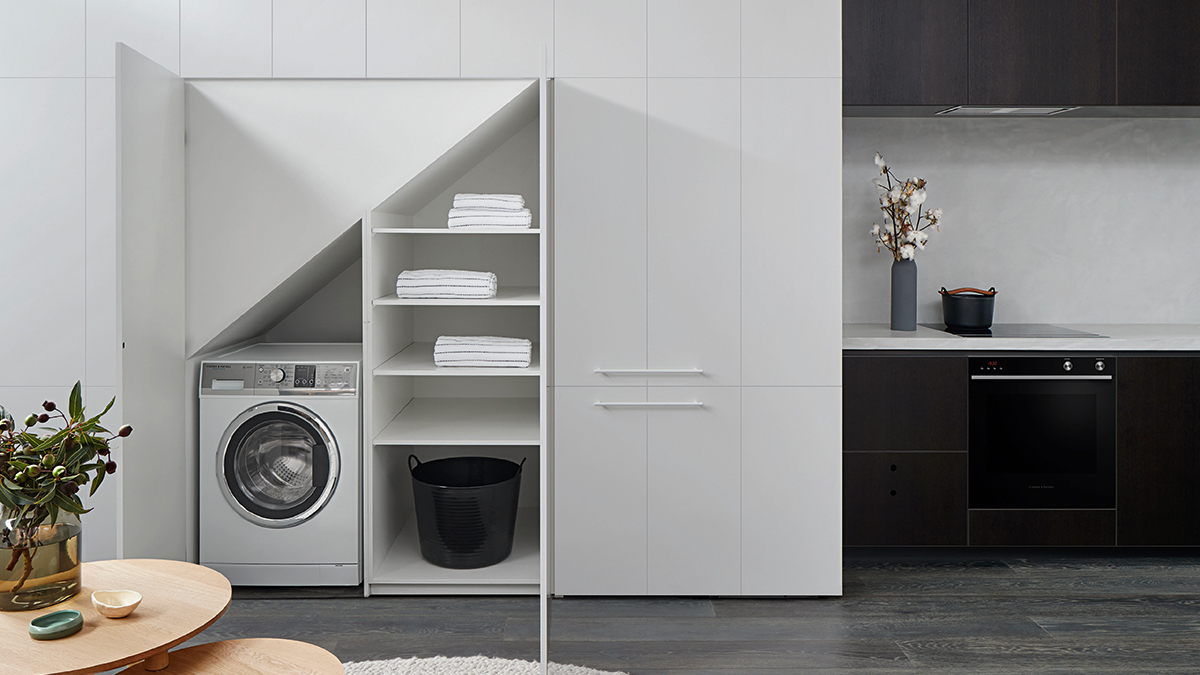 Compact black kitchen with a hidden laundry behind a white paneling wall and doors.