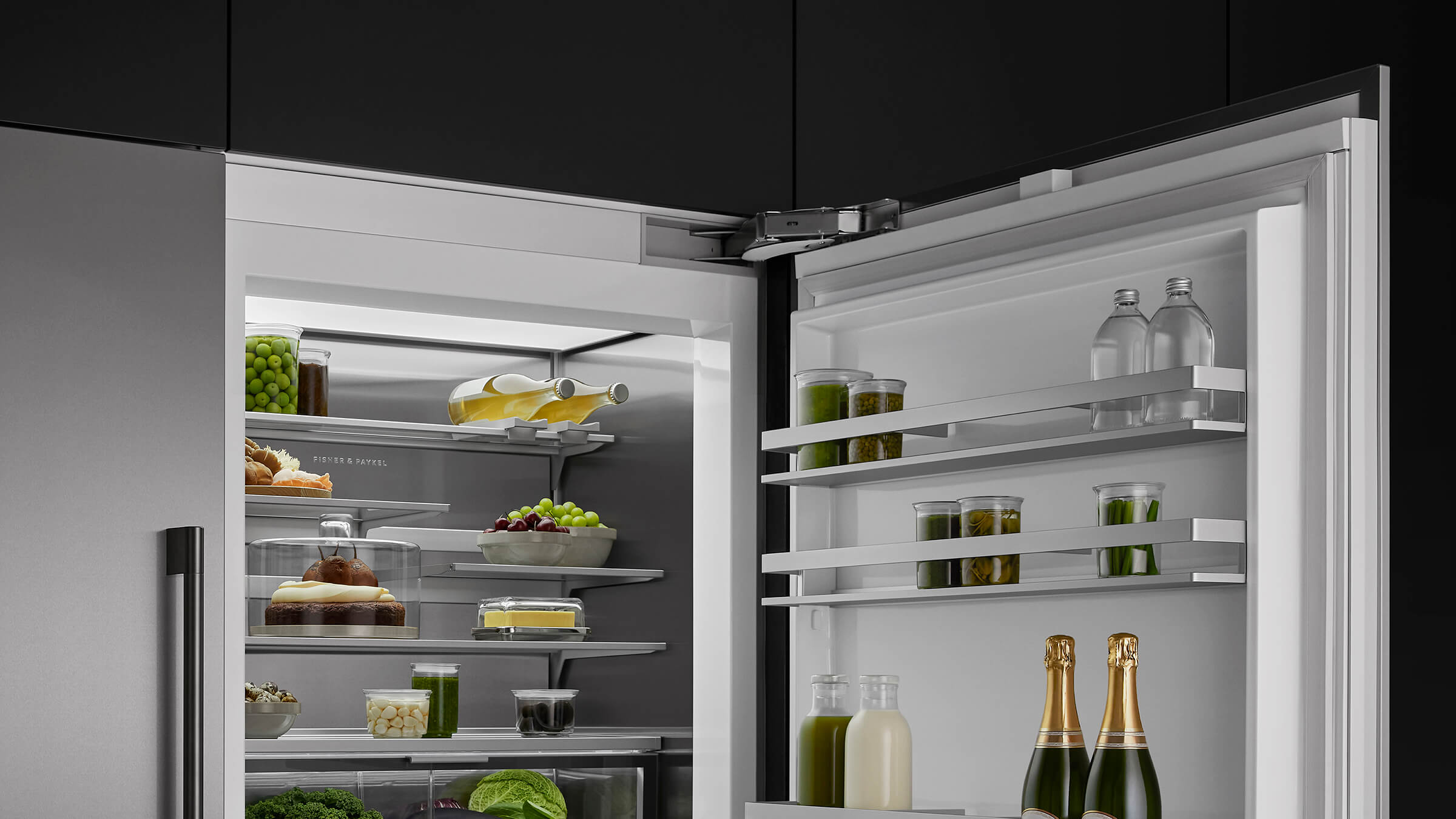 A trio of integrated refrigeration columns installed flush in a dark wood kitchen environment