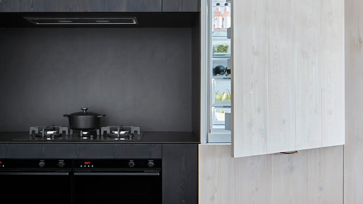 Black Ceramic Cooking Pot atop a Gas Cooktop next to an Open Refrigerator.