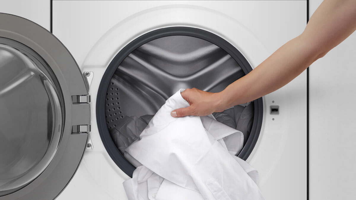 White Garment being loaded into Front Loader Washing Machine