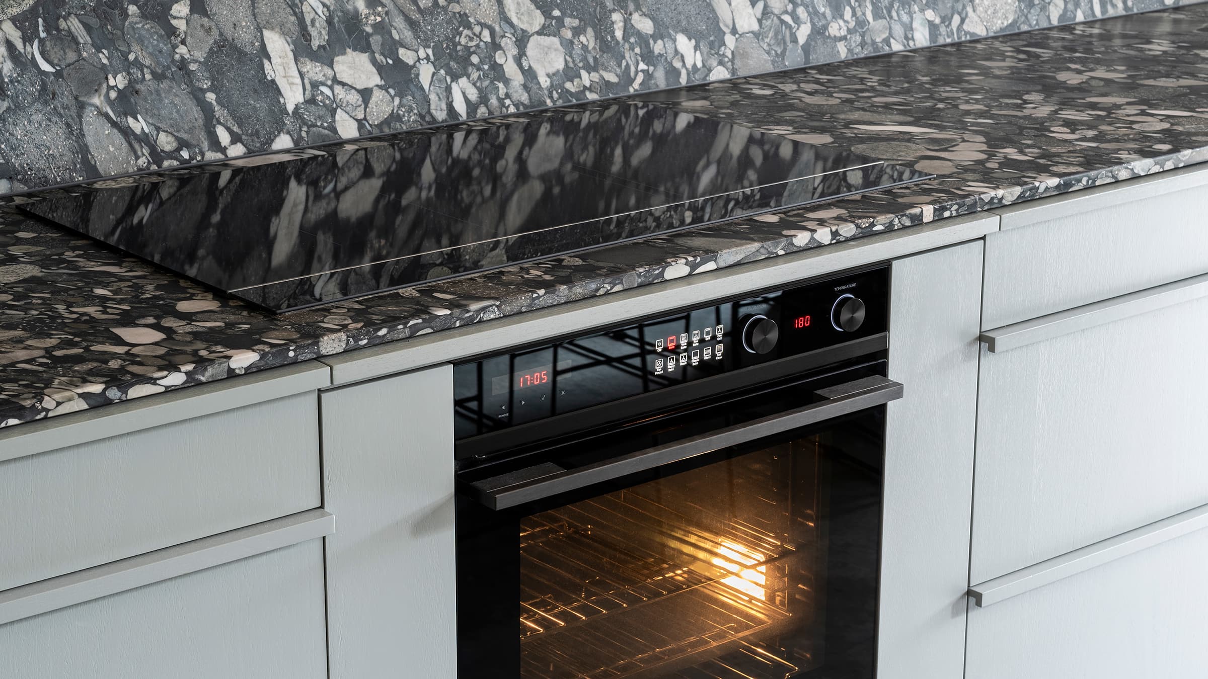 Side view of minimal cooktop on marble textured kitchen slab