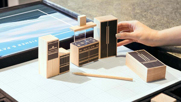 桌面上的格子纸上放着木制厨房电器模型和铅笔。