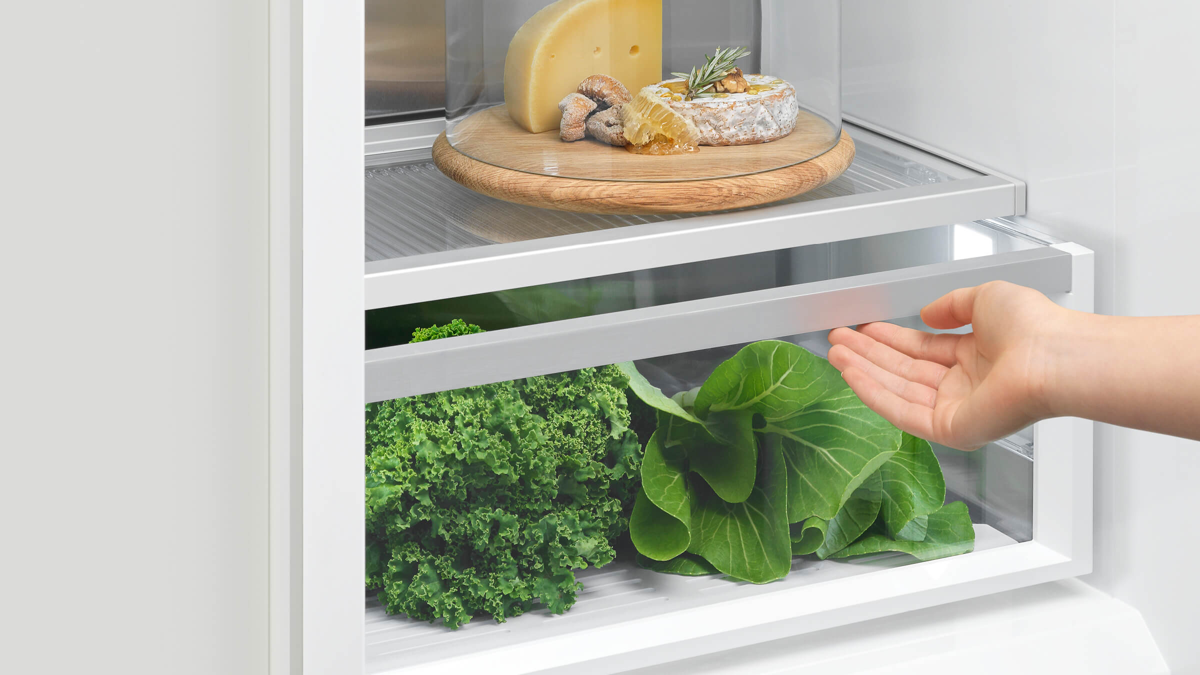 A hand reaching into an illuminated refrigerator column, highlighting easy access