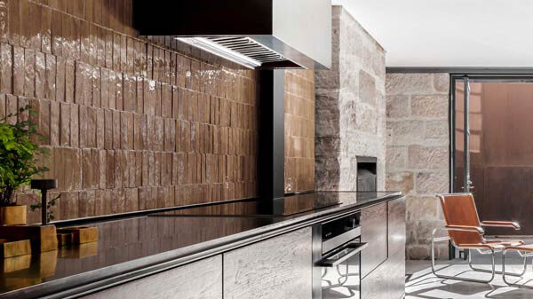 Modern Kitchen featuring Stainless Steel Backsplash, Granite Countertop, Espresso Coffee Maker atop a Black Glass Induction Cooktop and an Integrated Range Hood.