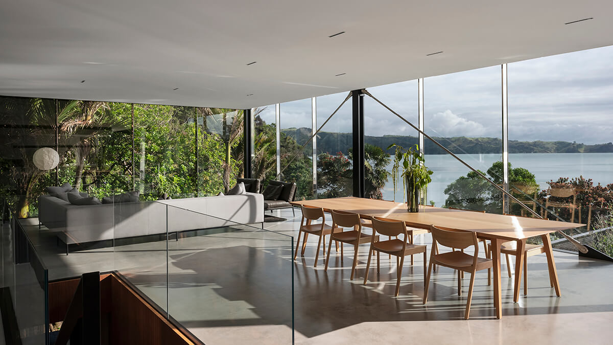 A view looking from the kitchen towards the dining and lounge area and out windows to the sea.