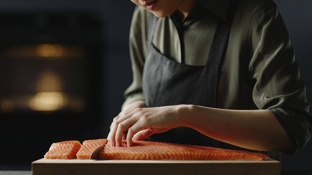 A chef preparing salmon on a chopping board
