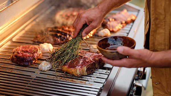 Bone-in Rib-Eye Steaks Being Seared atop a Stainless Steel Grill