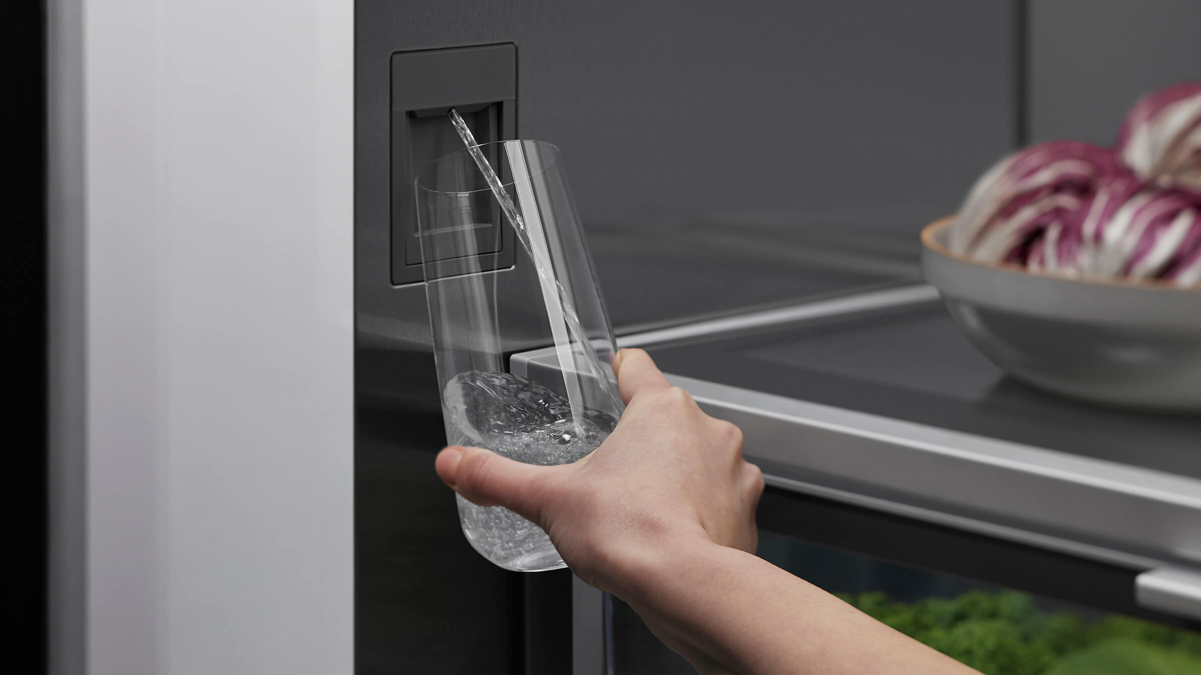 Person filling glass with filtered water from Fisher & Paykel refrigerator