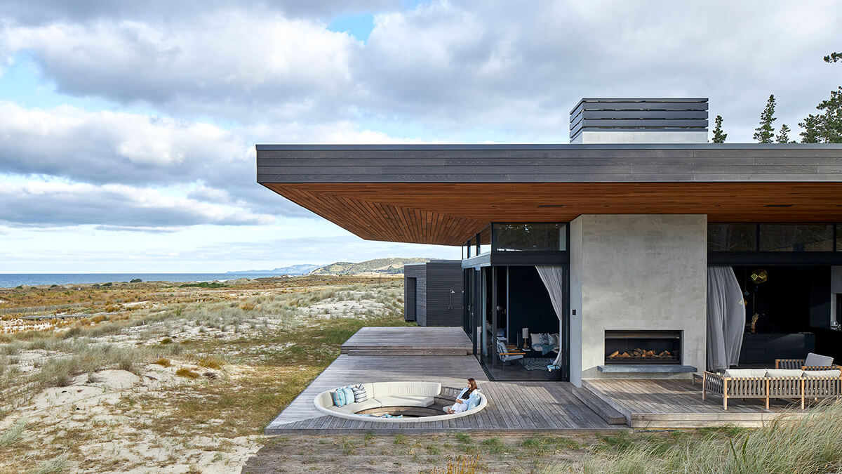 Exterior shot of Sandiland coastal house sunken fire pit and deck area