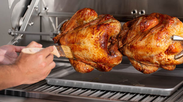 Close Up of Roasted Whole Chickens Being Glazed on Rotisserie Grill