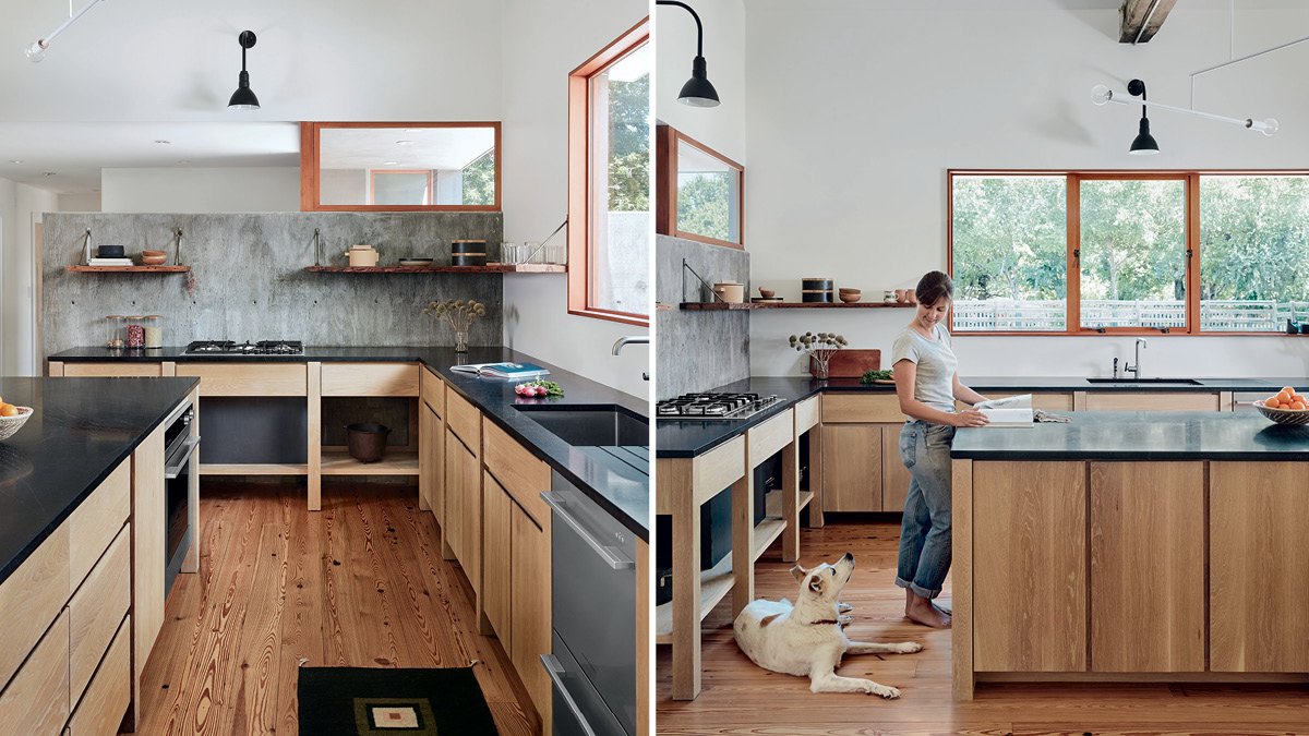 Standing woman in a kitchen reading a book and looking down at her white dog.