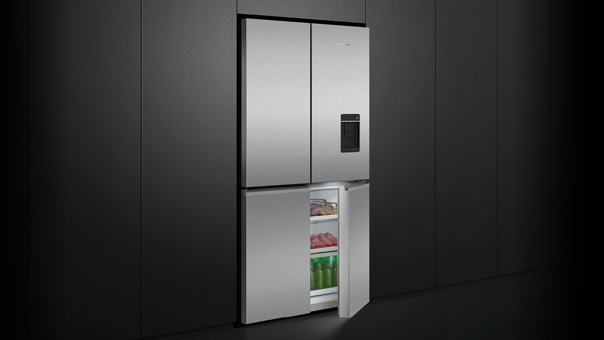 Fisher & Paykel Stainless Steel Quad Door Refrigerator with an Open Freezer Door surrounded by Black Panel Cabinetry.