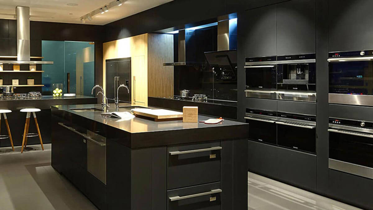 Table with Taps and Sinks Close to Lineup of Kitchen Appliances at Showroom.