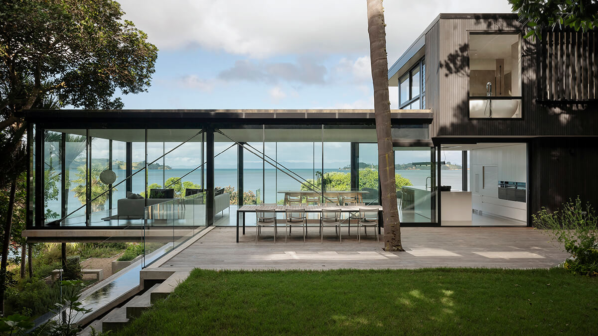 View through windows of Mahuika Beach House lounge, dining, kitchen area to the sea beyond